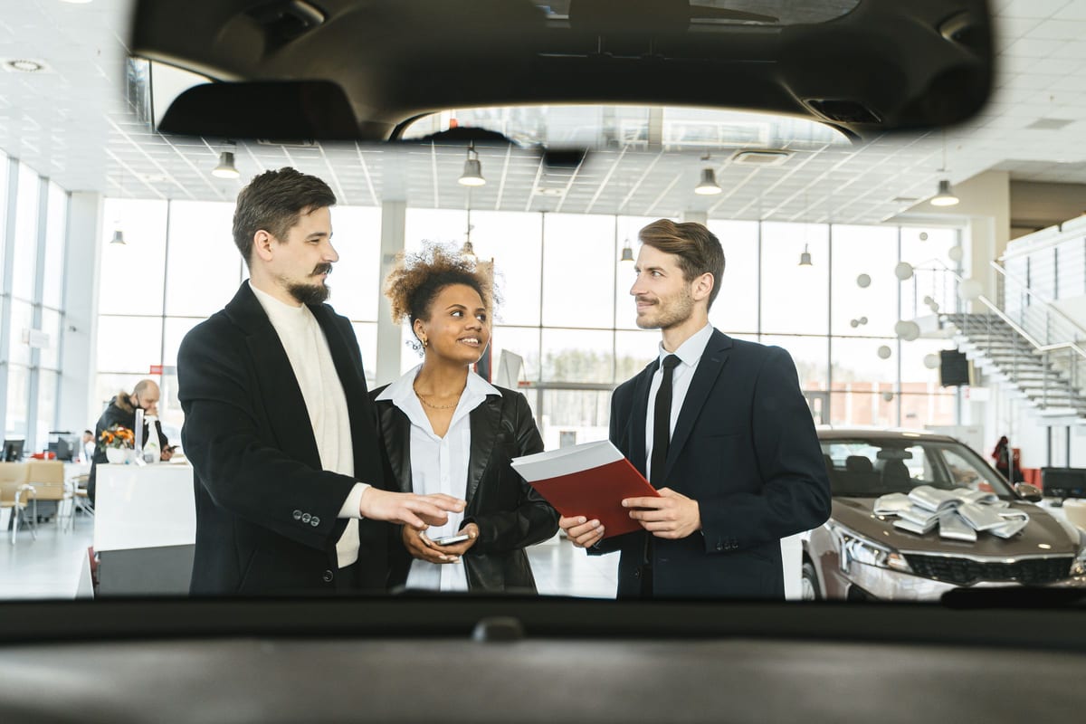 A sales consultation in progress on a dealership showroom floor, with vehicles in view